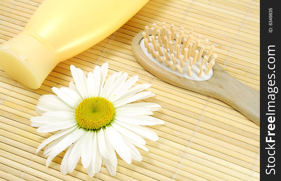 Shampoo and hairbrush on a bamboo