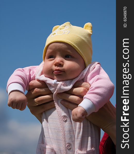 Little baby on mother's hands on blue sky background