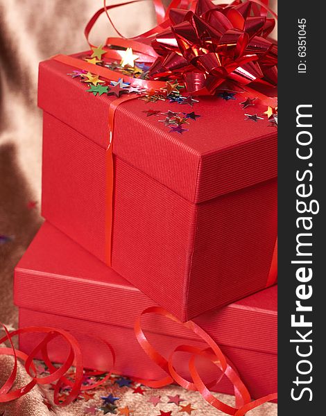 Red gift boxes with bows and stars on golden silk background