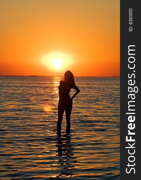 Silhouette of the young woman on a gulf on a sunset