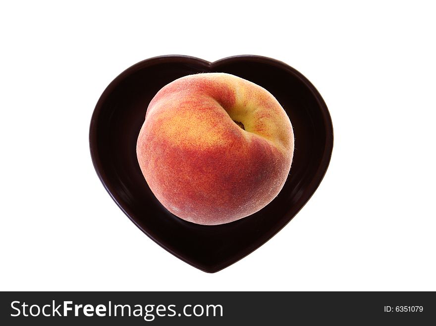 Peach lying on black heart isolated on white background