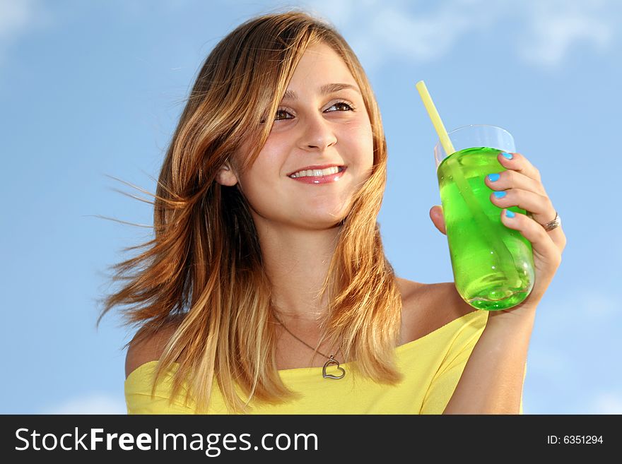 A wonderful young girl stands on a background dark blue sky and holds in a hand glass with drink