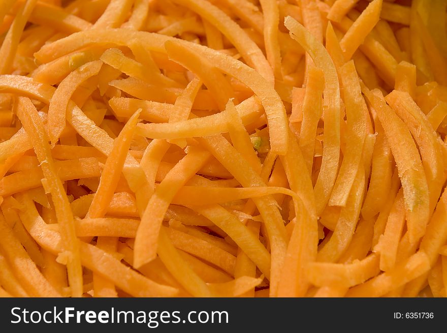 A pile of fresh coarsely grated carrot, ready to be used in a salad or for preparation of a dish.