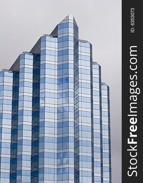 A modern blue and grey glass building on a grey background. A modern blue and grey glass building on a grey background