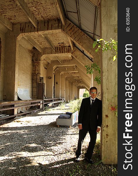 Handsome man wearing black suit in deserted location. Handsome man wearing black suit in deserted location