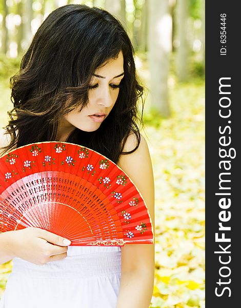 Young woman with red fan in a forest. Young woman with red fan in a forest.