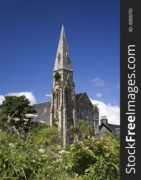 Overgrown steeple of a disused victorian church against blue sky. Overgrown steeple of a disused victorian church against blue sky