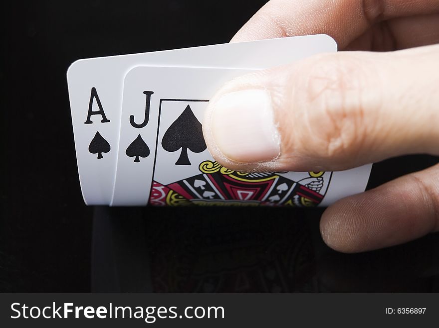 Blackjack cards held by hand against black background. Blackjack cards held by hand against black background