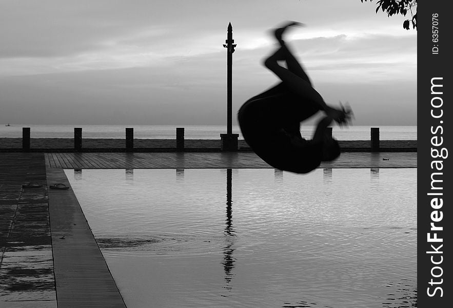 Silhouette Man somersault into Pool at holiday resort black & white. Silhouette Man somersault into Pool at holiday resort black & white