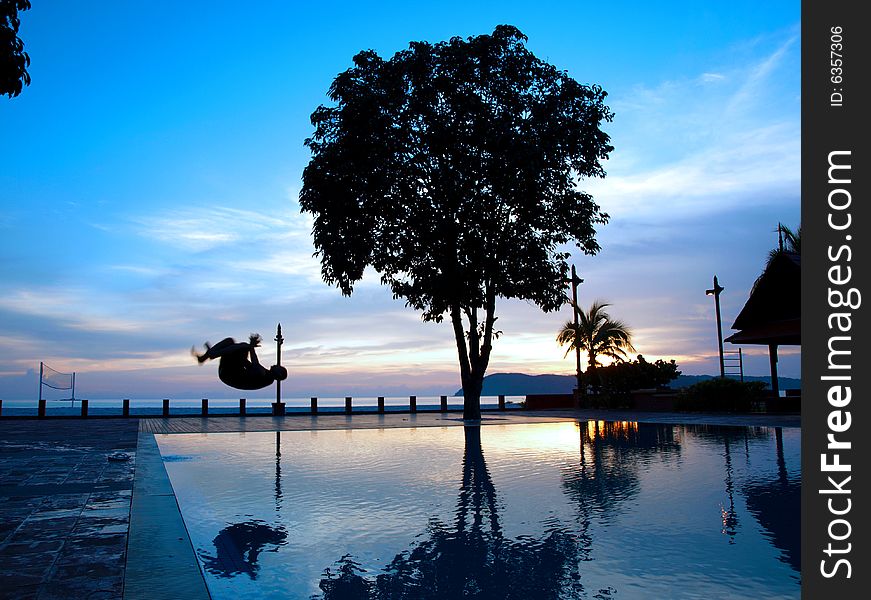 Silhouette Man somersault into Pool at holiday resort. Silhouette Man somersault into Pool at holiday resort