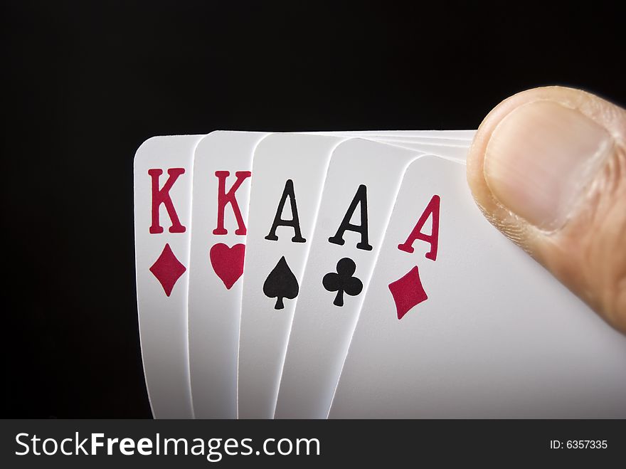 Three Aces and Two Kings held by hand against black background. Three Aces and Two Kings held by hand against black background