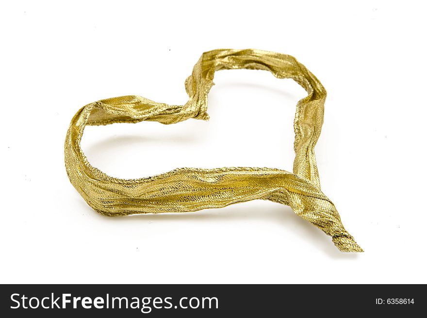 A golden ribbon shaped as a heart isolated on white. The focus is selective on the fronter part of the heart. Useful for christmas or valentines themes. A golden ribbon shaped as a heart isolated on white. The focus is selective on the fronter part of the heart. Useful for christmas or valentines themes.