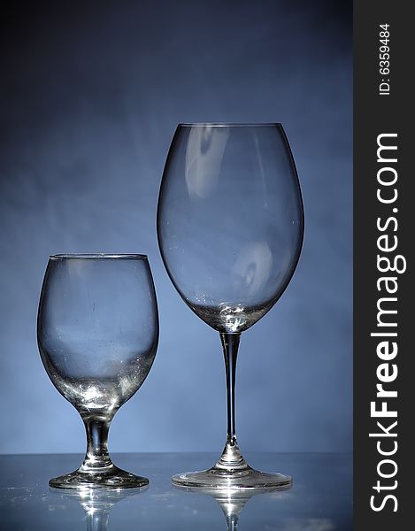 Two fine glasses standing next to each other on dirty blue background, like a tiny glass couple.