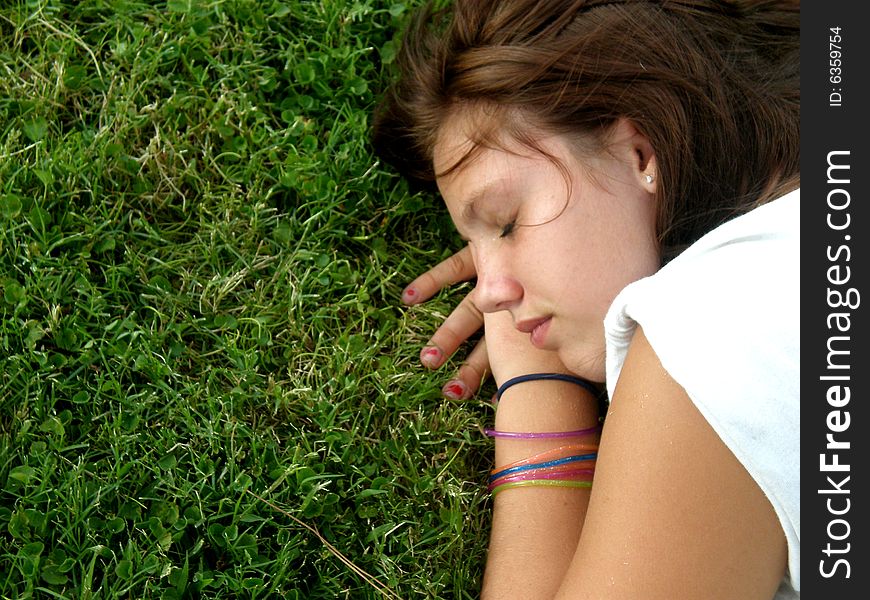 A picture of a young teen girl resting in the grass. A picture of a young teen girl resting in the grass.