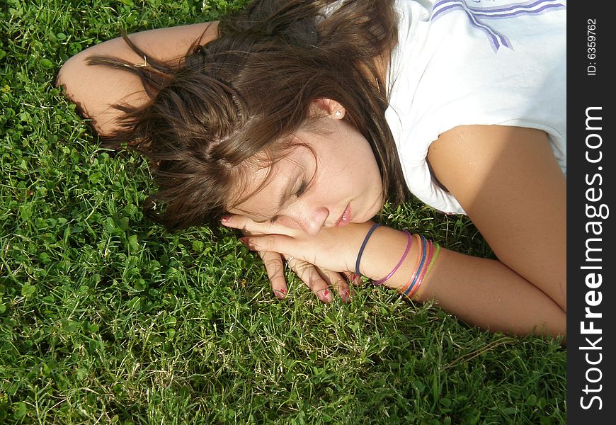 A picture of a young teen girl sleeping in the grass.