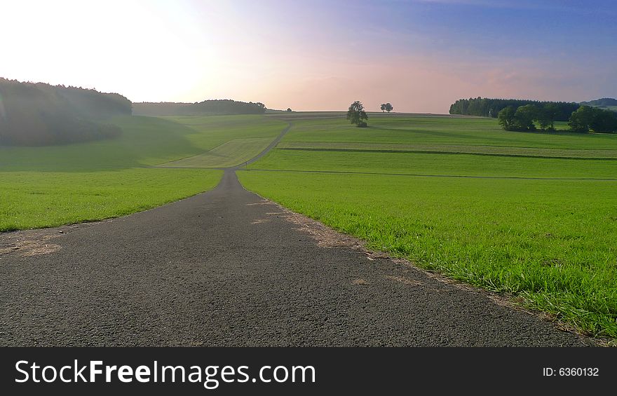 A wide open field on the Swabian Alb in south western Germany with a country road leading into nowhere