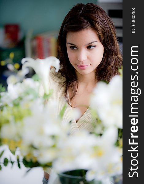 A pretty young woman arranging flowers in the kitchen. A pretty young woman arranging flowers in the kitchen