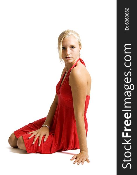 Beuatiful blonde teenage girl sitting on floor in red dress