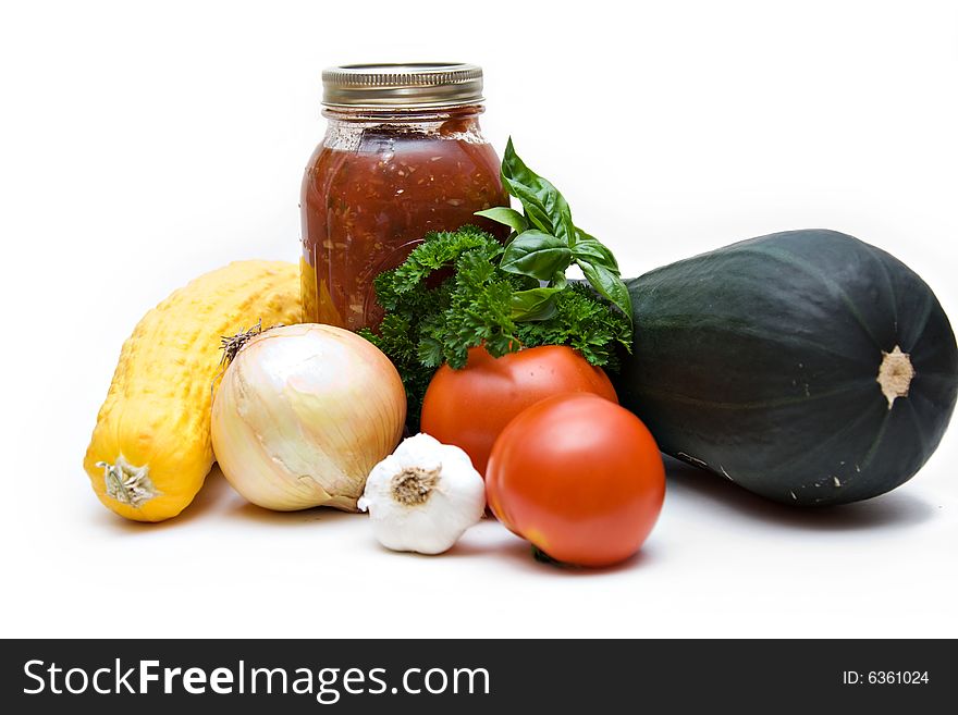 Fresh garden vegetables and also a jarred of canned tomatoes on white background.