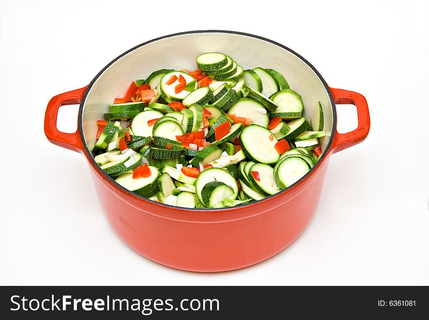 A large cast iron enameled pot filled with fresh garden chopped zucchini, red peppers, green peppers, onions and garlic being prepared for a pasta sauce. A large cast iron enameled pot filled with fresh garden chopped zucchini, red peppers, green peppers, onions and garlic being prepared for a pasta sauce.