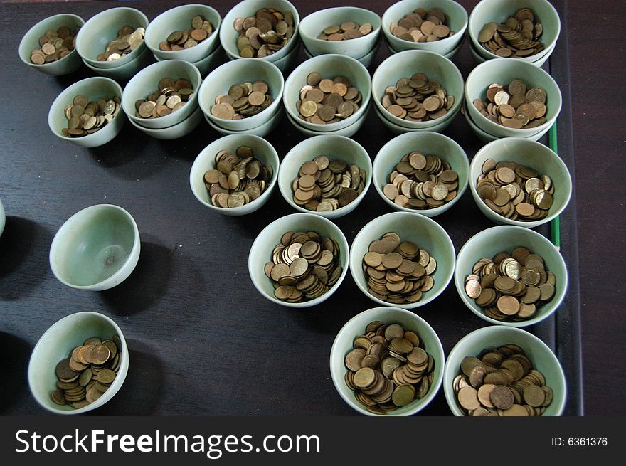 Bowls containing coins for offering in a Buddhist temple. Bowls containing coins for offering in a Buddhist temple
