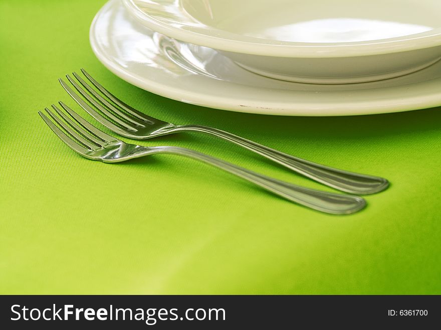 Two folks and plate in a green table. Two folks and plate in a green table