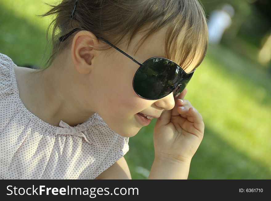 Beautiful girl in sun glasses on a background a green grass. Beautiful girl in sun glasses on a background a green grass