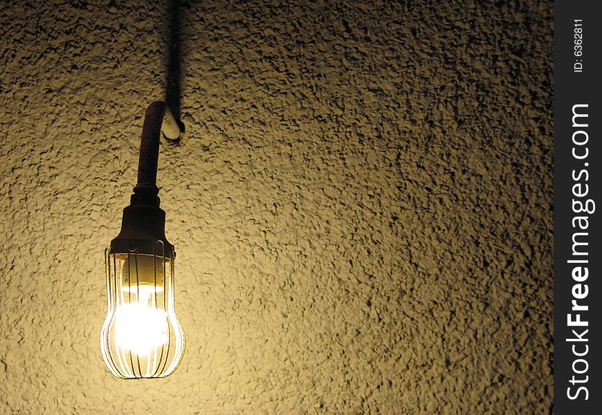 Lit lightbulb in front of a wall