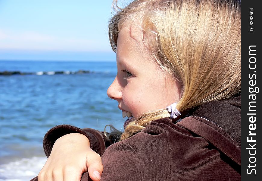 Young blond girl smiling at seaside - close up