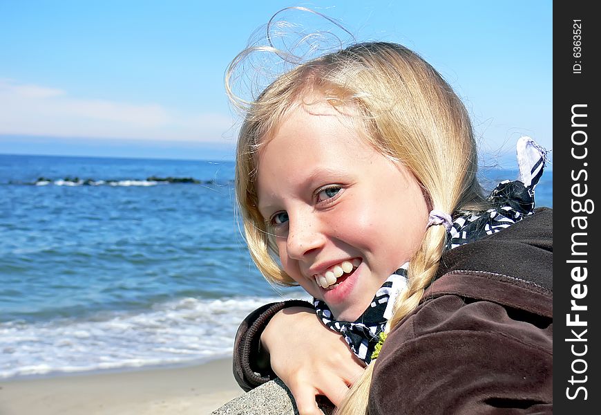 Young blond girl smiling at seaside - close up