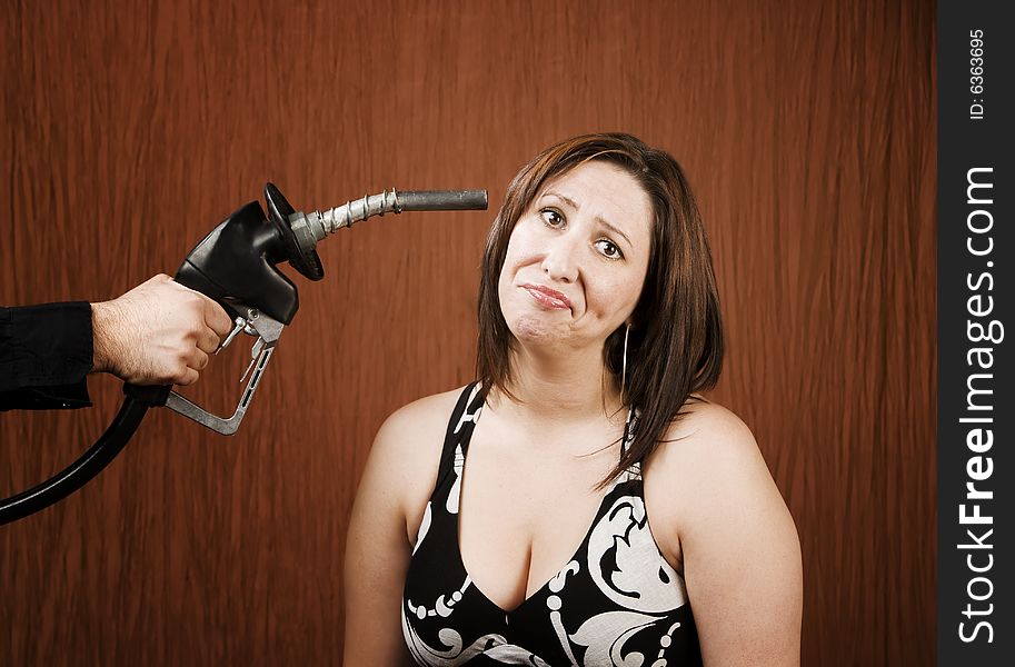 Woman with a gas nozzle pointed like a gun to her head. Woman with a gas nozzle pointed like a gun to her head
