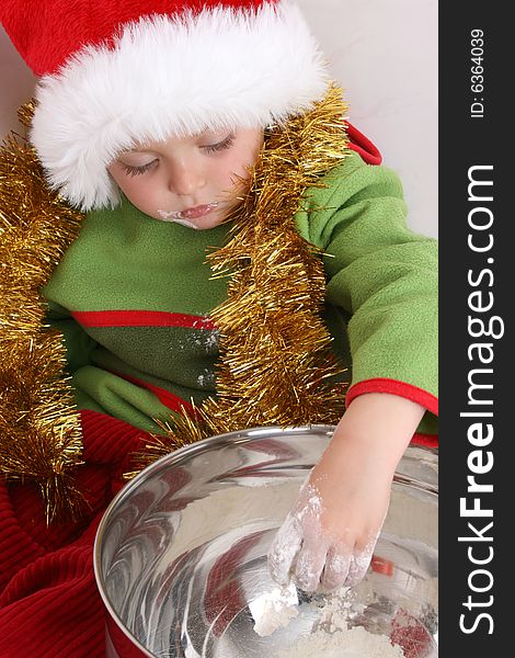 Toddler wearing a christmas hat, baking christmas cookies