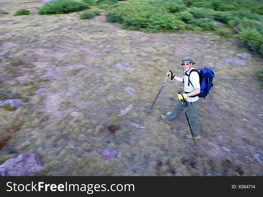 One person walking along trail with brush and mountains in background. One person walking along trail with brush and mountains in background