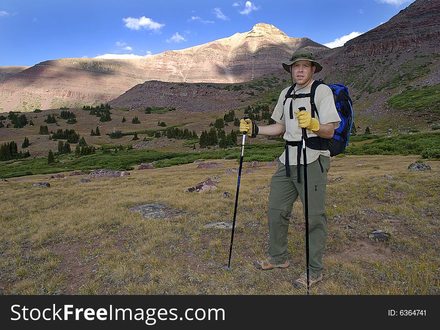 One person walking along trail with brush and mountains in background. One person walking along trail with brush and mountains in background