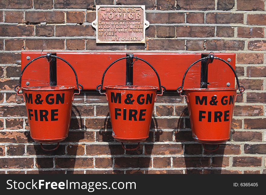 Three red fire buckets on hooks ready for an emergency. Three red fire buckets on hooks ready for an emergency