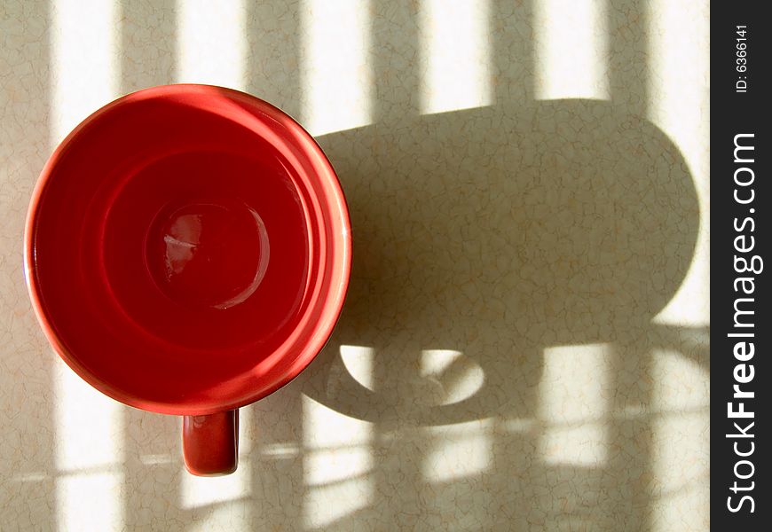 Red round cup reflects upon a table