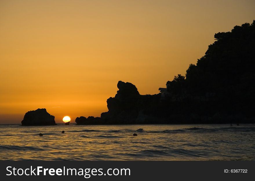 Sunset over Greece seen from Corfu island with rocks in foreground. The sea is the Ionian sea. Sunset over Greece seen from Corfu island with rocks in foreground. The sea is the Ionian sea.