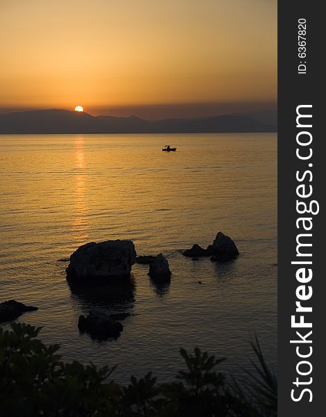 Surise over Greece seen from Corfu island with rocks in foreground. The sea is the Ionian sea. Surise over Greece seen from Corfu island with rocks in foreground. The sea is the Ionian sea.