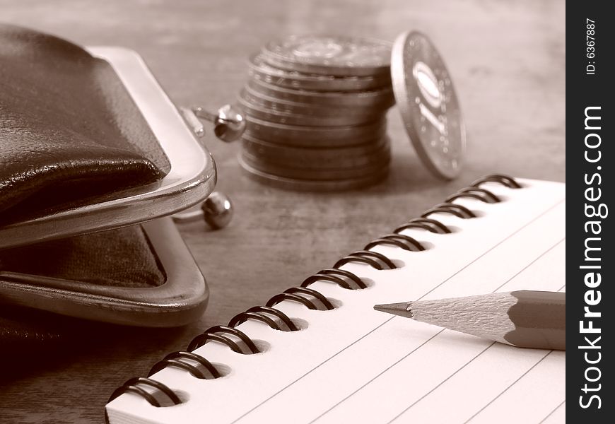 Sepia toned notepad with pencil and purse with coins stack. Sepia toned notepad with pencil and purse with coins stack