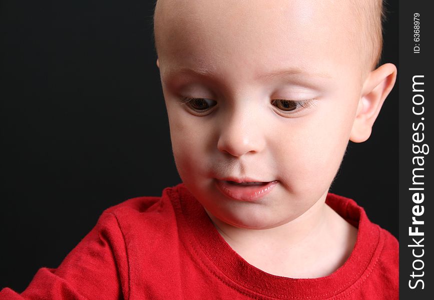 Blond toddler against a black background with a serious expression