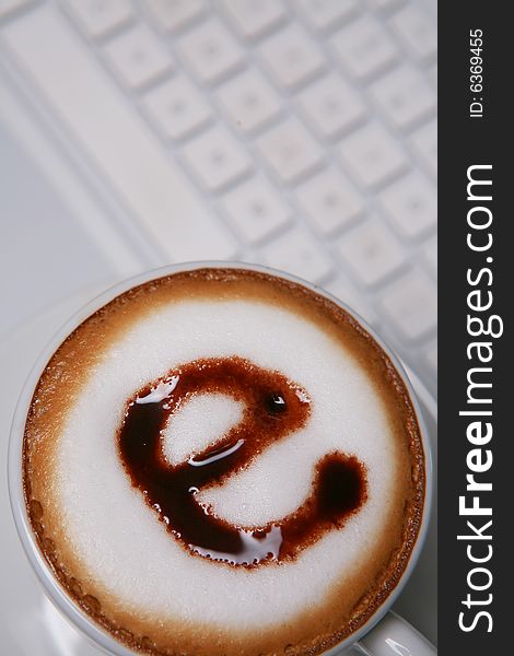 Coffee with e sign on white keyboard. Coffee with e sign on white keyboard