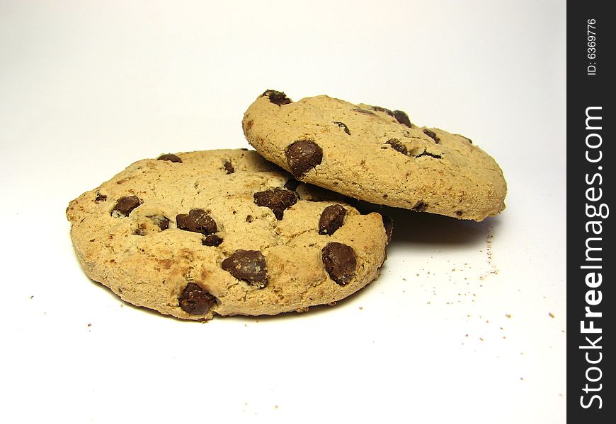 Two chocolate chip cookies, on stacked on the other, with a white background.