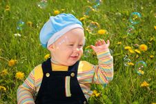 Child Sits On Grass And Looks On Soap Bubbles Stock Photography Child Sits On Grass And Looks On Soap Bubbles Stock Photography
