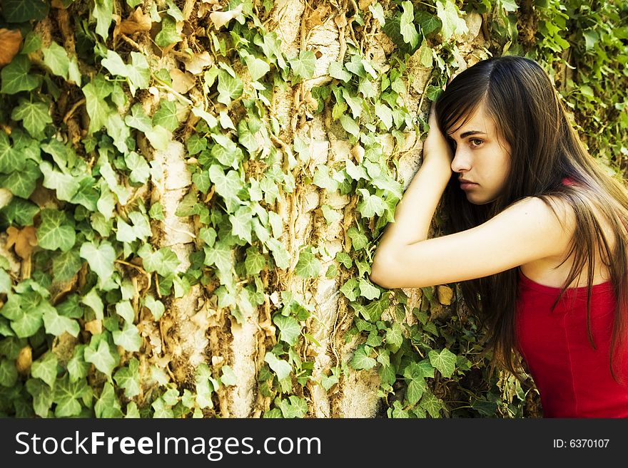 Young woman on wall full of leaves.
