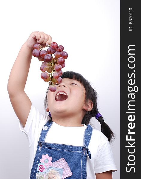 Little girl eating red grape on white. Little girl eating red grape on white