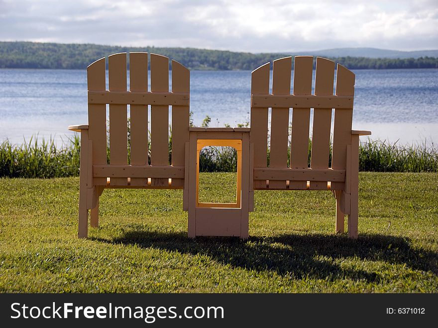 A pair of yellow Muskoka Chairs facing a lake