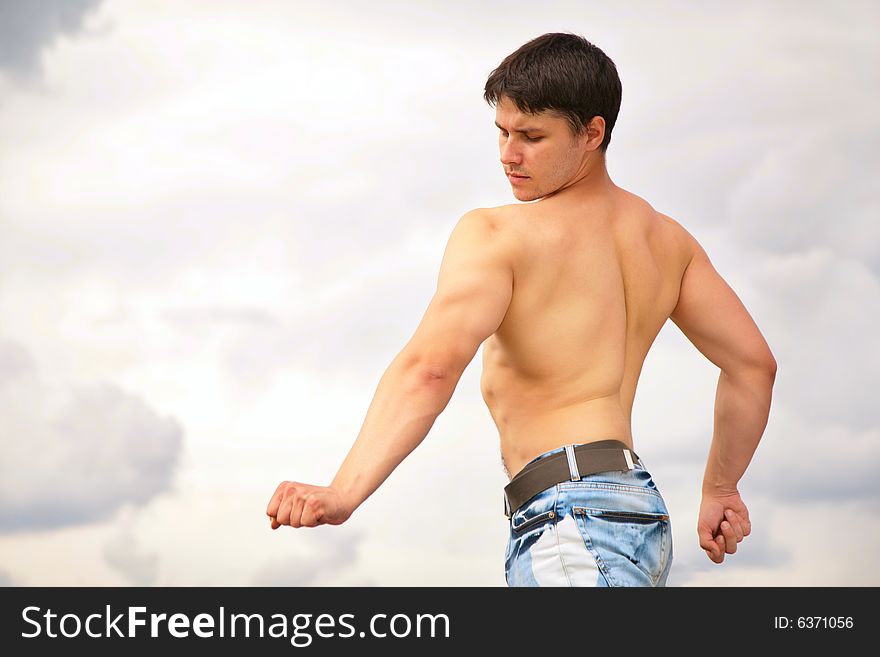 Young bodybuilder on cloudy background