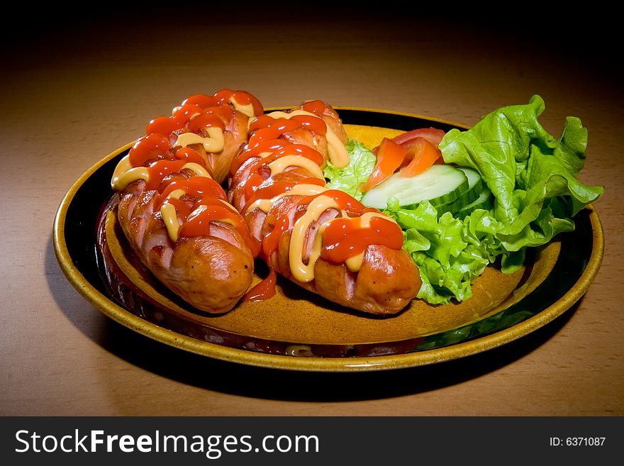 Sausages on plate with tomatoes and salad. Sausages on plate with tomatoes and salad