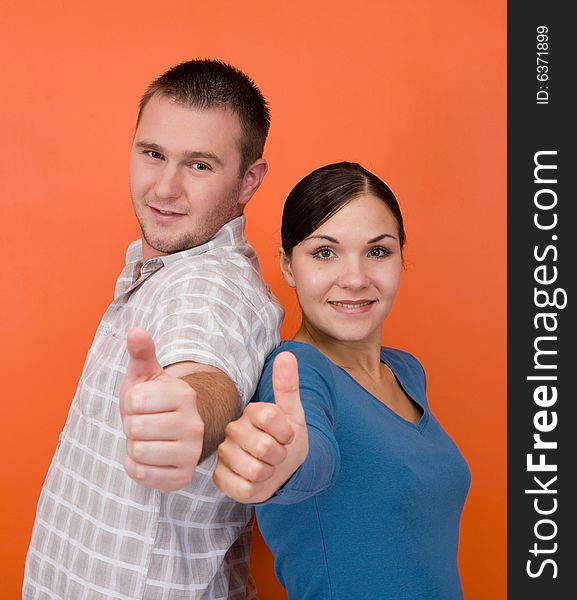 Casual couple together standing on orange background. Casual couple together standing on orange background
