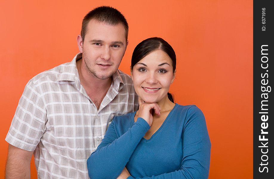 Casual couple together standing on orange background. Casual couple together standing on orange background